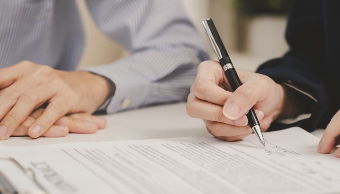 Two business people holding pen and signing a contract 